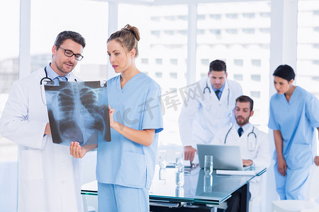医生在背后使用笔记本电脑与同事一起检查 X 射线