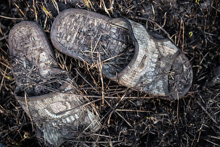 烧焦的草地上的旧烧焦鞋