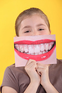 大嘴人摄影照片_女孩把她牙齿的放大照片放在嘴前