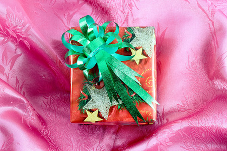 礼盒绿色摄影照片_粉红色缎带上带绿色丝带的红色礼盒
