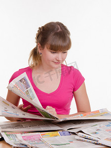 女孩翻阅报纸以找到合适的广告