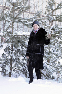 穿着黑色皮大衣的快乐女人在白雪皑皑的别针上花费了