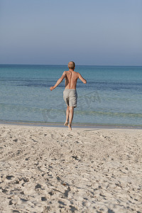 男人在沙滩上奔跑在水中的肖像