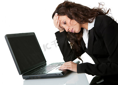 头疼女摄影照片_在笔记本电脑上工作的压力大的女商人