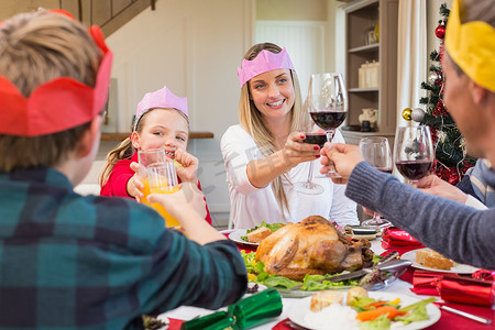 戴着派对帽的家人在圣诞晚餐上敬酒