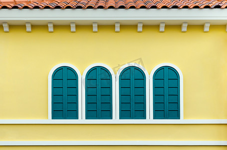 黄色页摄影照片_黄墙上的四扇绿色拱形窗户