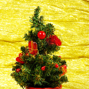 圣诞树木摄影照片_金色背景上带礼物的小装饰圣诞树