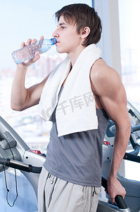 黑色背景摄影照片_健身房喝水的男人