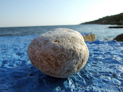 石头堆摄影照片_深蓝色表面上更大的鹅卵石。
