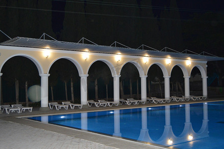 开封夜景摄影照片_带柱子和拱门的豪华游泳池的夜景，倒映在水中