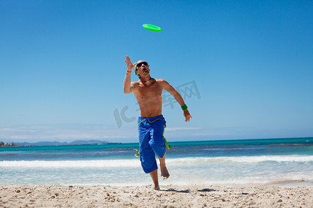 夏天在海滩上玩飞盘的迷人男人