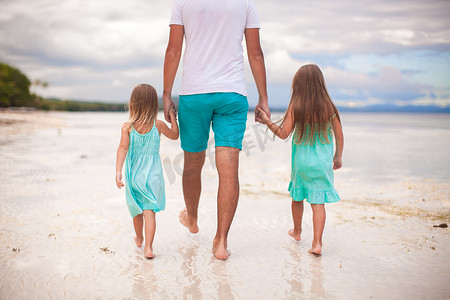父亲和他的两个孩子在海边散步的背影