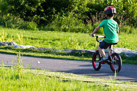 骑自行的男孩摄影照片_在公园的自行车道上骑自行车的儿童