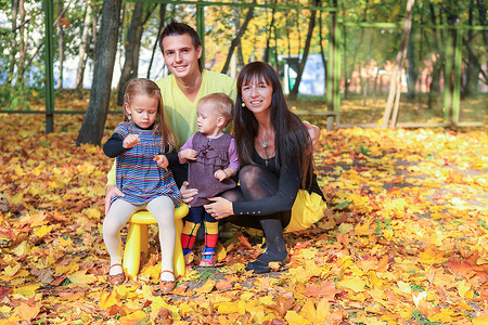 年轻的父母带着两个小女儿在黄秋公园享受天气