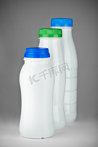 乳白色的液体摄影照片_灰色背景上孤立的白色瓶子