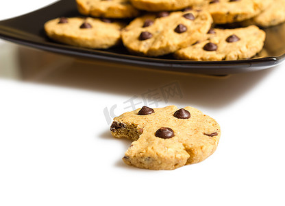 一堆饼干零食摄影照片_一口巧克力饼干，盘子里放着一堆饼干