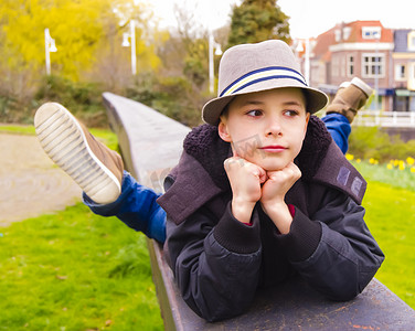 栏杆背景摄影照片_可爱的十几岁男孩躺在公园的栏杆上
