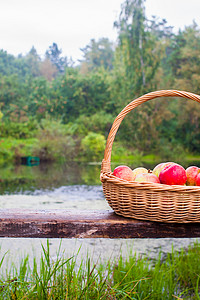 湖边长凳上放着红黄苹果的大草篮特写