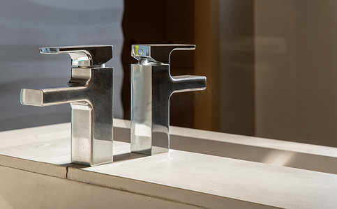 水盆摄影照片_有镀铬物水龙头和白色铺磁砖的现代卫生间水盆。