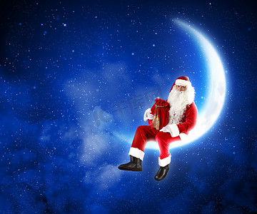 装饰的月亮摄影照片_坐在月亮上的圣诞老人照片