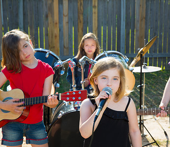 儿童乐队摄影照片_儿童歌手女孩在后院唱歌演奏现场乐队