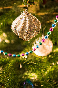 金色灯光背景摄影照片_圣诞树装饰品在树闪闪发亮的灯光下的特写