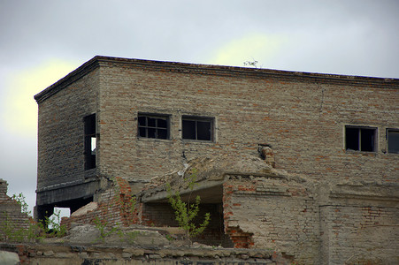 破旧工厂建筑摄影照片_旧工厂背景下破旧的砖砌建筑。
