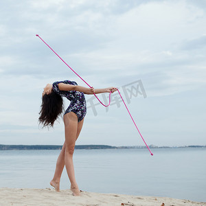 小猴子跳绳摄影照片_与跳绳的年轻体操运动员女孩跳舞