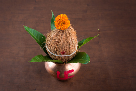 卡拉什摄影照片_铜卡拉什与椰子和芒果叶与木制背景上的花卉装饰。