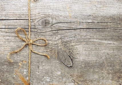 蝴蝶结绳子摄影照片_在旧木头上系成蝴蝶结的绳子