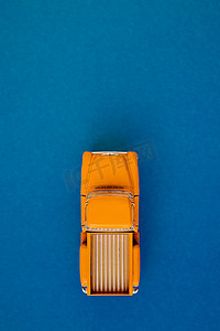 蓝紫色图摄影照片_蓝紫色背景上的黄色复古汽车皮卡。