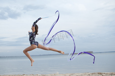 年轻的体操运动员女孩用丝带跳舞