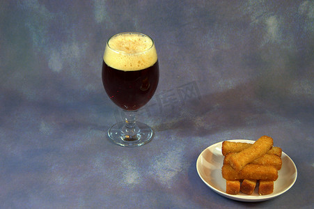 面包丁摄影照片_一杯黑啤酒和一盘小麦面包丁。