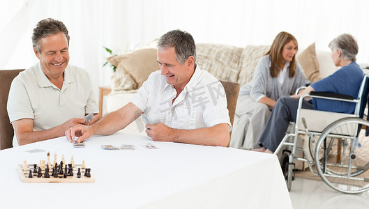 打牌摄影照片_男人在妻子聊天时打牌