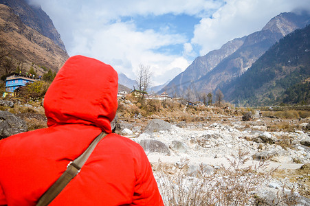 欧洲美女摄影照片_活跃的高级尼泊尔美女穿着红色冬季夹克，看着山和蓝天背景。