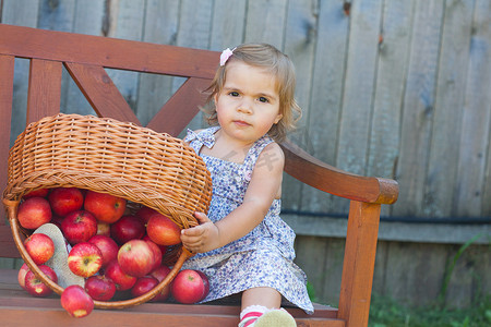 穿着夏装的小女孩坐在一家带苹果的木店里