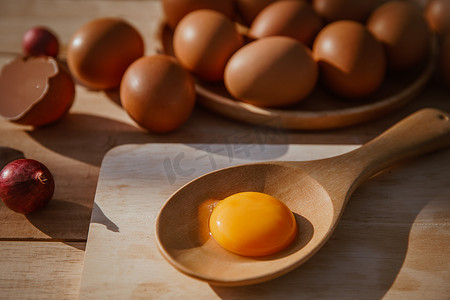 破了的鸡蛋摄影照片_鸡蛋放在木托盘上，鸡蛋破了。