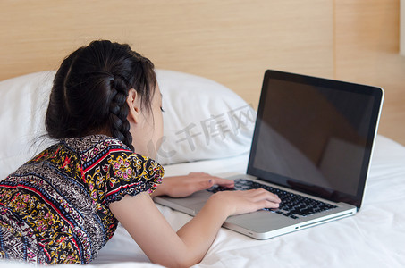 玩电脑的人摄影照片_躺在床上玩电脑的女孩