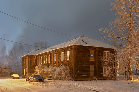 老房子雪摄影照片_一条多雪的冷淡的街道上的老木房子在夜照明