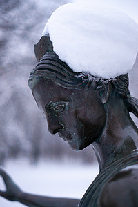 雕塑青铜摄影照片_一个女人在冬季雪地公园的青铜纪念碑。