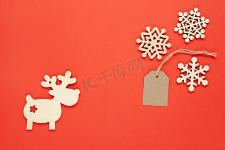圣诞装饰雪花摄影照片_圣诞装饰，三个小木雪花，工艺标签，鲜红色背景上的鹿。