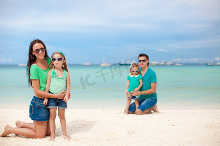 妈妈和大女儿在沙滩上，爸爸和小女儿在沙滩上