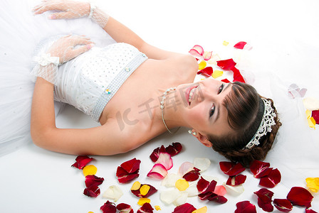 在地板上的美丽的新娘在红色玫瑰花瓣中