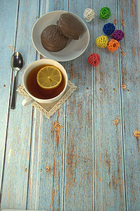 一杯柠檬茶、一把勺子和一盘巧克力蛋糕放在一张装饰着五颜六色球的木桌上。
