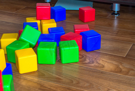 木地板上散落着五颜六色的儿童游戏塑料立方体