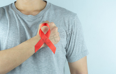 战天摄影照片_艾滋病意识，男性手拿着红色的艾滋病意识丝带。