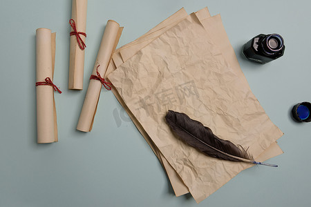 墨水瓶羽毛笔摄影照片_红色背景上的乌鸦羽毛、墨水瓶和旧黄纸。