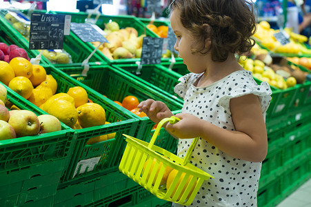 蔬菜超市摄影照片_小女孩在超市买柠檬。