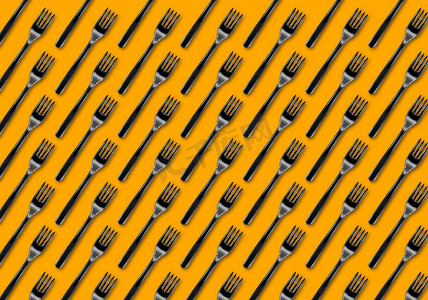 黄色背景中的许多黑色塑料叉子，顶视图