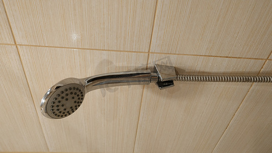 洗澡摄影照片_淋浴喷壶固定在墙臂上。